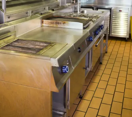 Puertas Corredizas de Acero Inoxidable ¡Descubre sus características! 4 Interior de una cocina industrial con un mueble al centro que tiene un mueble con estufa y tarja con repisas inferiores con puertas corredizas de acero inoxidable