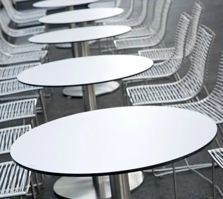Construye paso a paso tu propia mesa de acero inoxidable ¡Es muy sencillo! 9 Mesas de acero inoxidable redondas puestas en fila a manera de comedor en un sitio exterior, a cada lado de las mesas se encuentran varias sillas en fila.