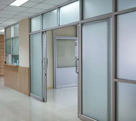 Puertas Corredizas de Acero Inoxidable ¡Descubre sus características! 3 Interior de un edificio donde al centro hay una puerta corrediza enfrentada abierta con herrajes y perfiles de acero inoxidable.