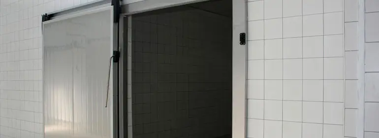 Puertas Corredizas de Acero Inoxidable ¡Descubre sus características! 1 Puerta corrediza de acero inoxidable abierta de un cuarto de refrigeración decorado con azulejo color blanco