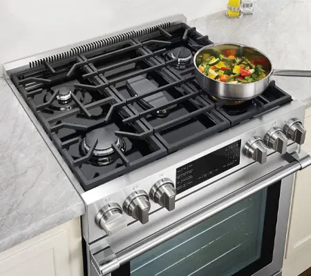 Pasos para limpiar Estufa de Acero Inoxidable 2 Vista frontal de una estufa de acero inoxidable de seis quemadores con una olla donde se cuecen verduras