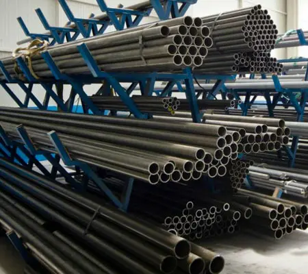 Acero al carbono vs acero inoxidable: diferencias clave y cuándo usar cada uno 1 Tuberías de acero al carbono apiladas dntro de una bodega