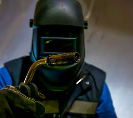 Soldadura de aluminio: Descubre 8 Técnicas para hacerlo efectivamente 3 Persona con equipo de protección mostrando una antorcha para soldadura MIG